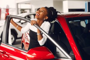 Happy Lady smiling while coming out of a red car